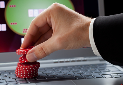 Player placing chips on a laptop which shows an online casino - online gambling concept; focus on the chips